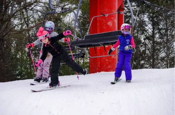 three children ski off of lift