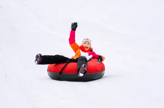 child waves from snow tube