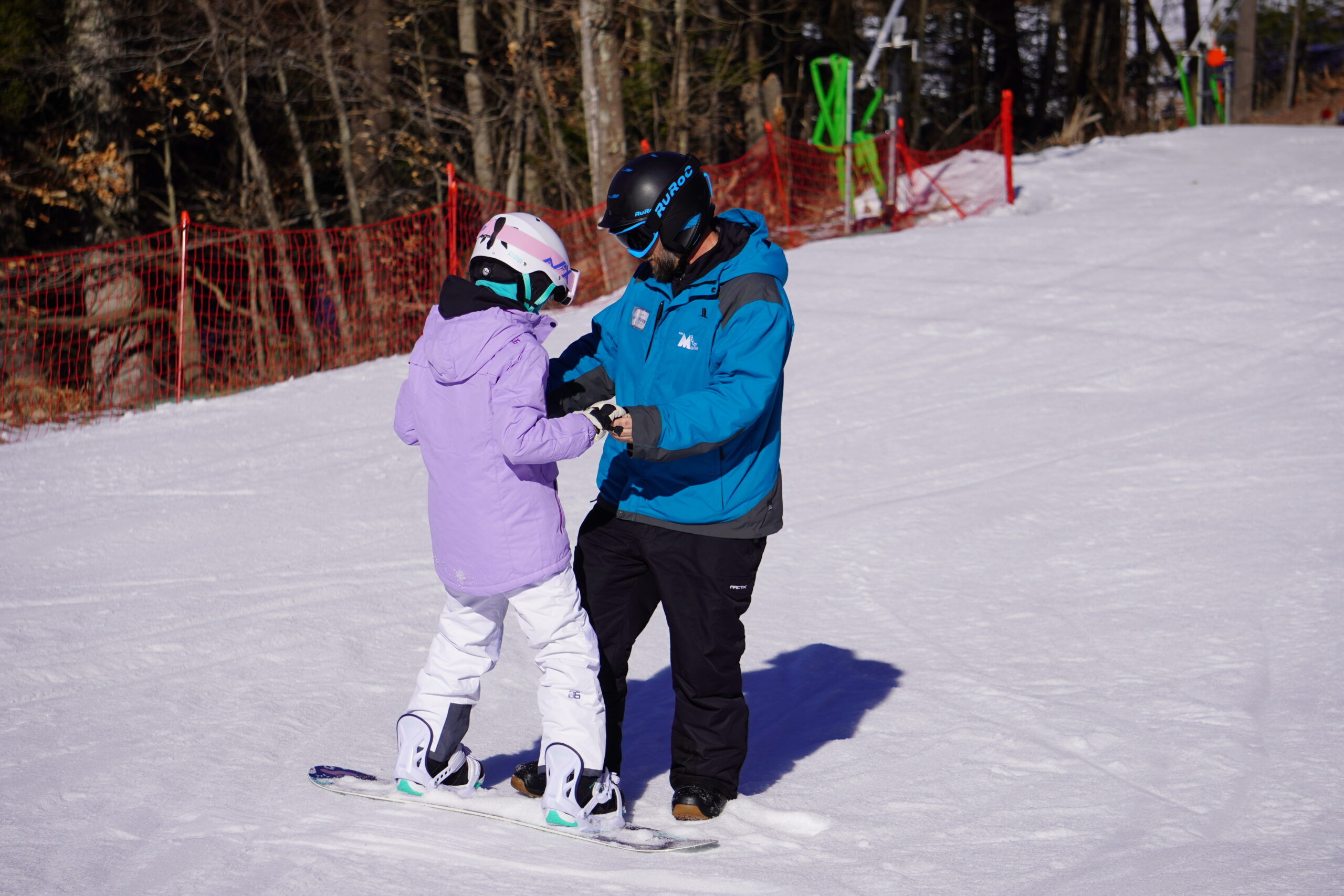 Snowboard instructor helping a young snowboarder